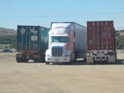 Photo 18: Three semi-trucks are parked and stored at a vacant parcel of land.