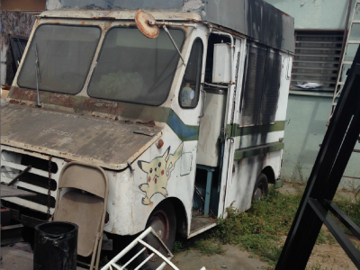 Photo 23: An old ice cream truck with flat is stored in a residential yard.