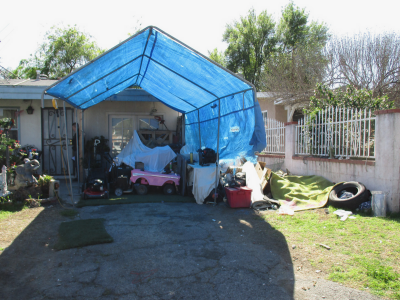 Photo 45: Broken machinery, toys, discarded cloth materials and tarps are maintained on a residential property.