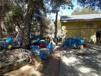 Photo 46: Multiple bags of trash and discarded tarps are maintained on a residential property.