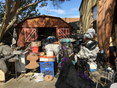 Photo 47: Broken and discarded furniture, boxes and bagged items, and discarded cloth materials are maintained in the yards of a residential property.