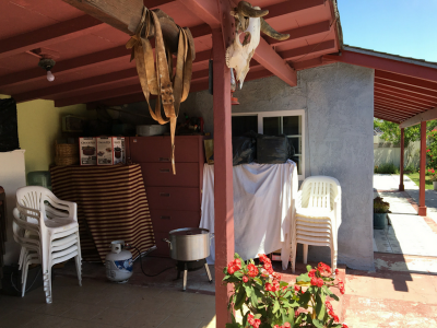 Photo 50: Stacks of plastic chairs, furniture, cooking goods, and other miscellaneous items are stored under a patio cover, but outside of an enclosed structure.