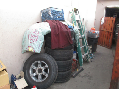 Photo 51: Tires, auto parts and supplies, and cleaning supplies are stored outdoors in a residential driveway.